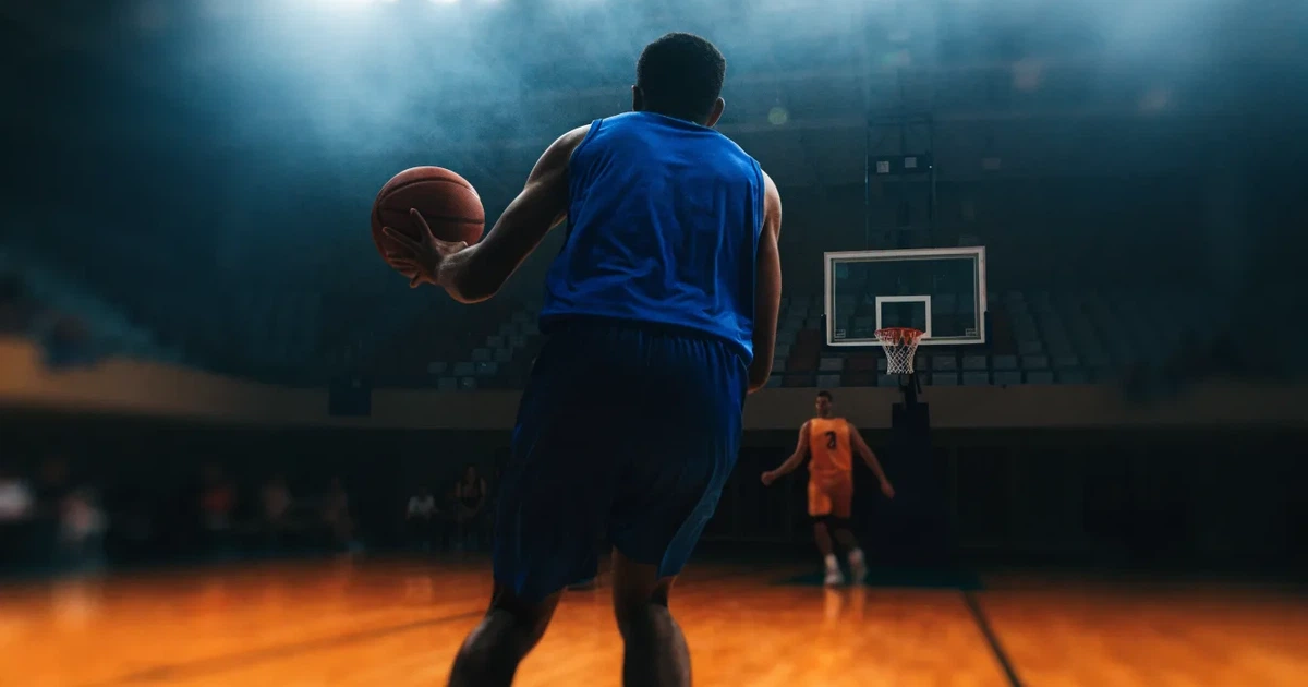 Eine leere Basketballhalle mit glänzendem Parkett und einem Korb im Hintergrund, Licht von Deckenstrahlern spiegelt sich im Boden.